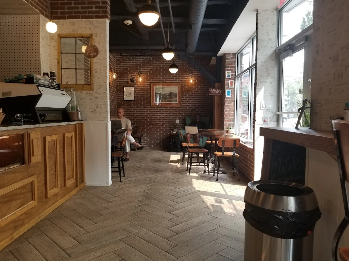 Kaffa interior — exposed brick, warm light, herringbone floors